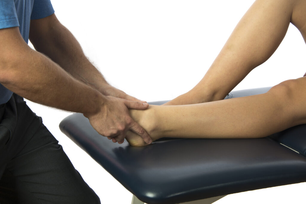 Physiotherapist performing treatment on patients ankle.