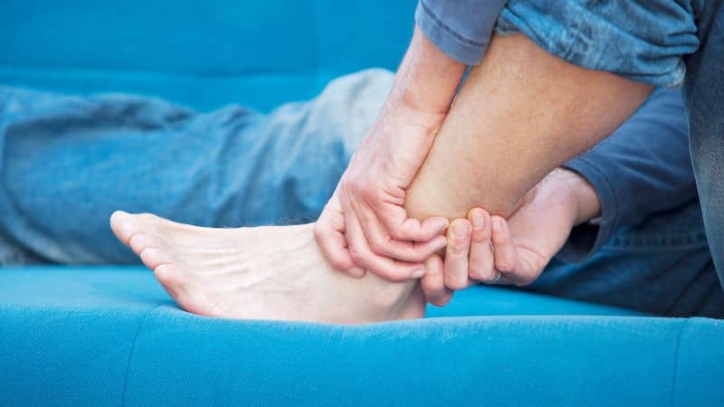 person with ankle sprain sitting on couch in pain