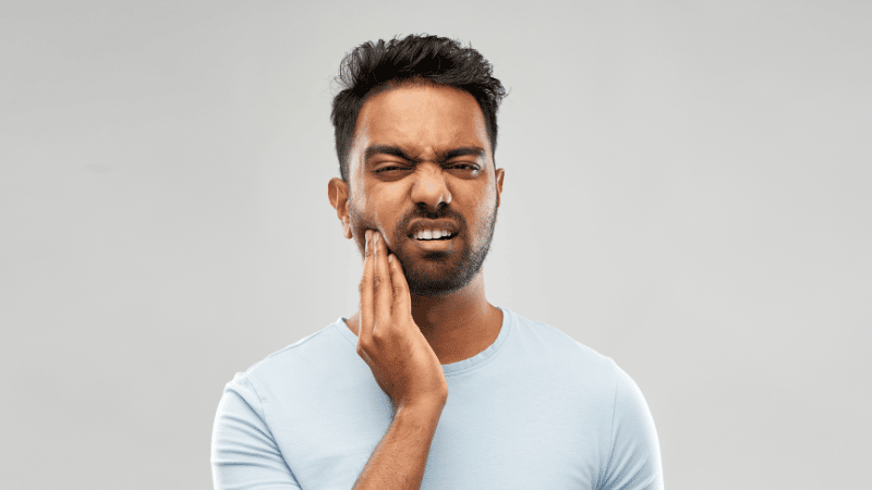 Man with temporomandibular disorder holding his jaw