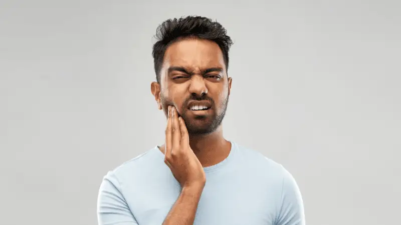 Man with temporomandibular disorder holding his jaw