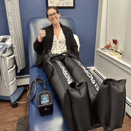 female patient giving thumbs up while using normatec leg compression sleeves